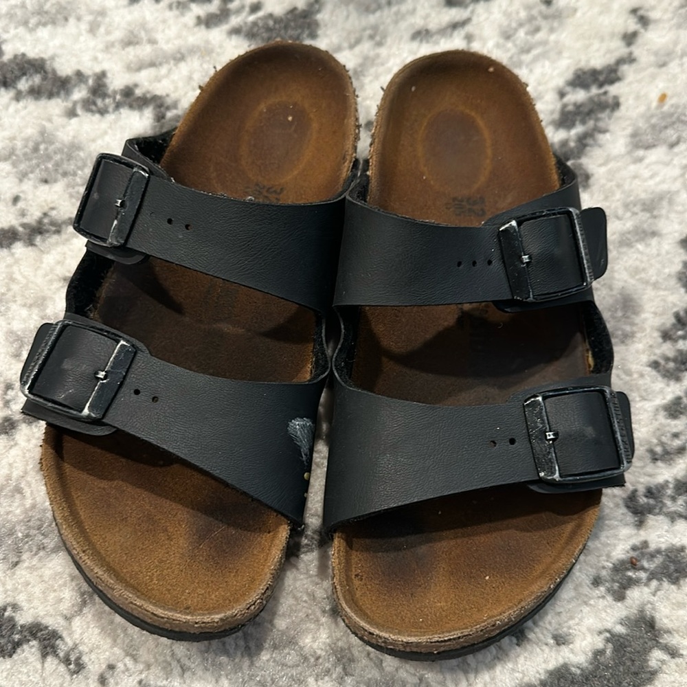 Black leather Birkenstocks with a little mark on it